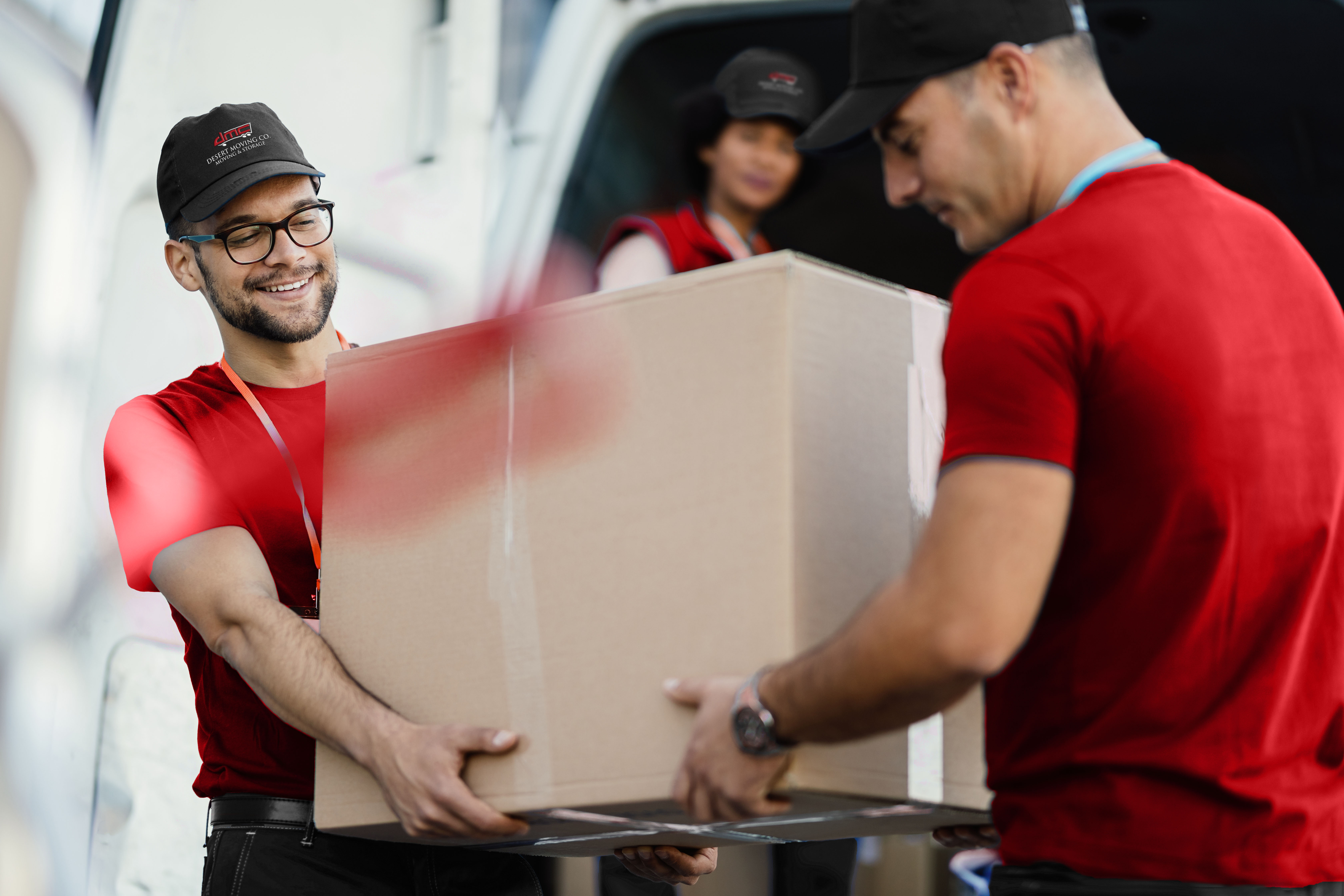 Three Desert Moving movers unloading large box from van